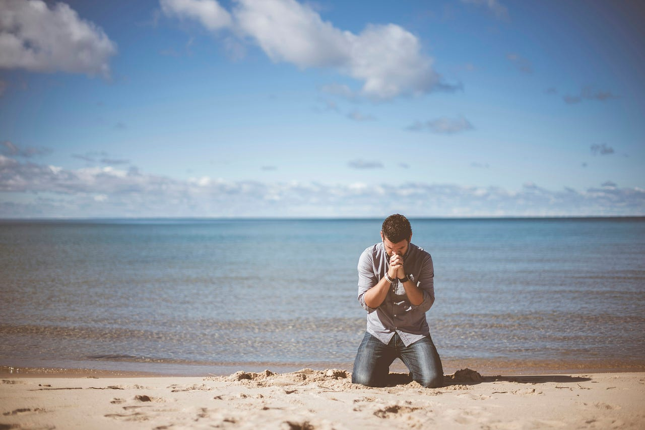 Man kneeling in the sand deep in gratitude