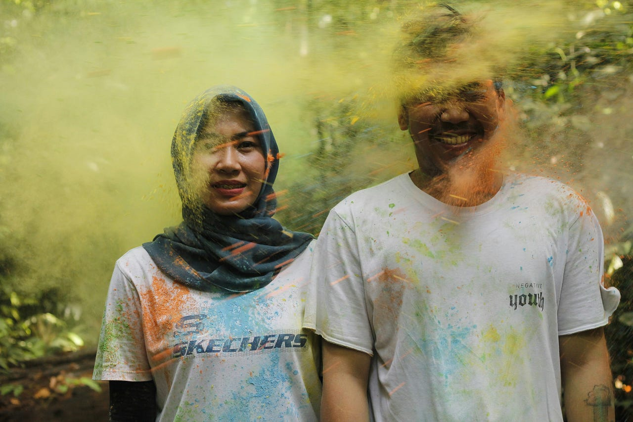 A couple getting sprayed with colors, smiling