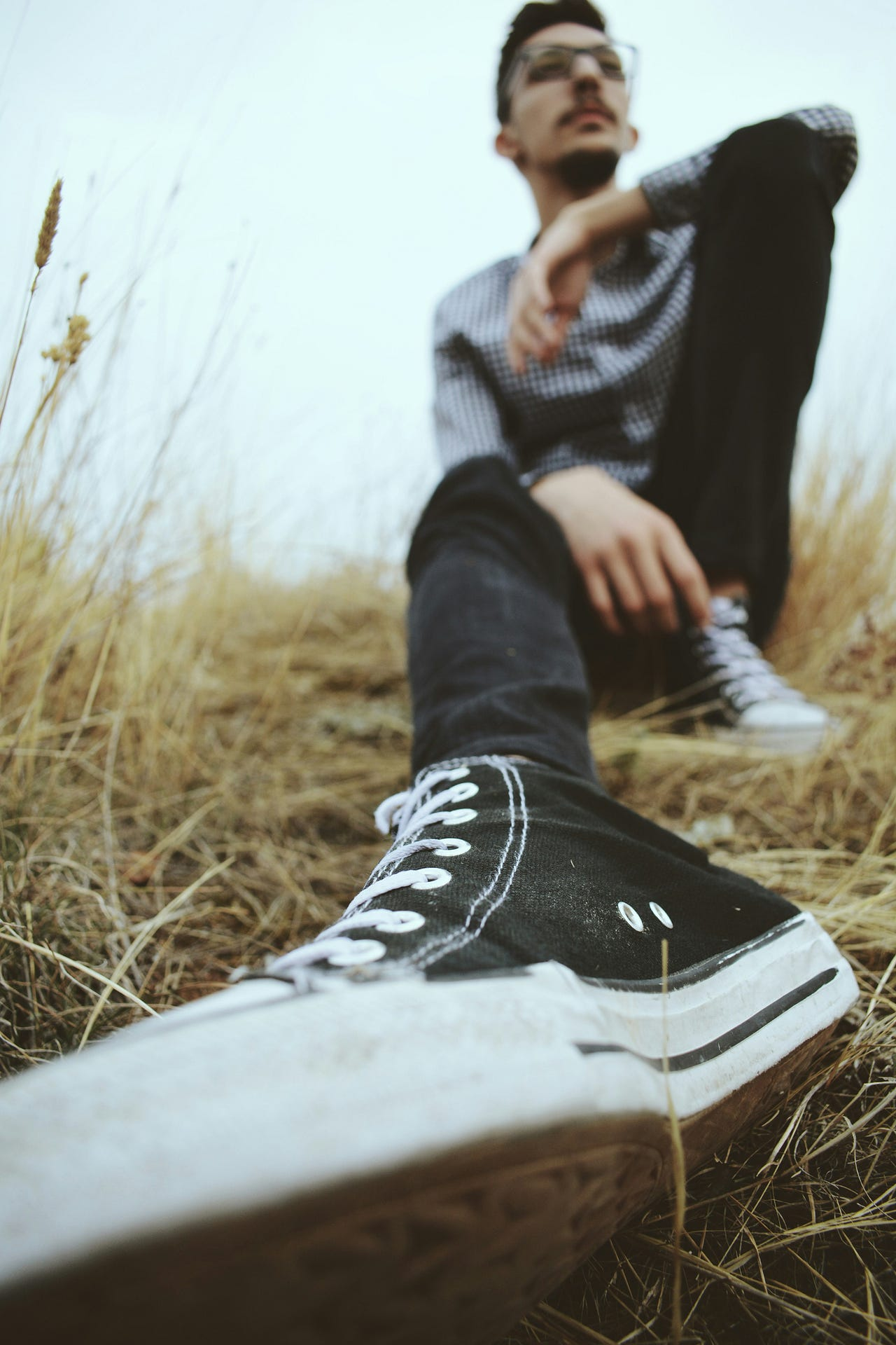Image of man sitting in the grass with his shoe near the camera lens