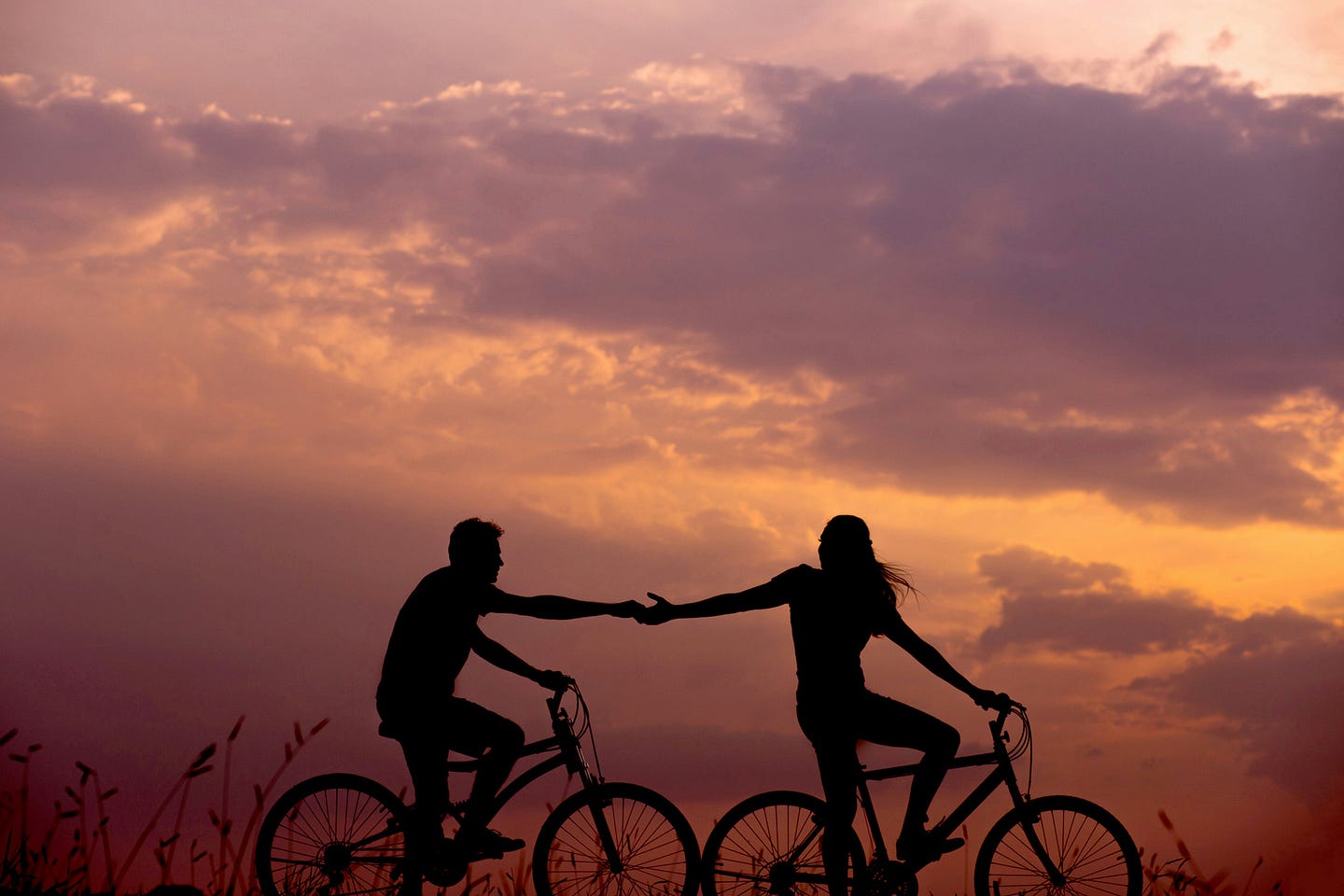 A couple holding hands while riding bikes